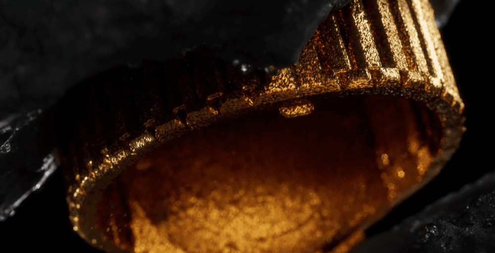 An extreme close-up focuses on the golden, textured metallic band of the watch