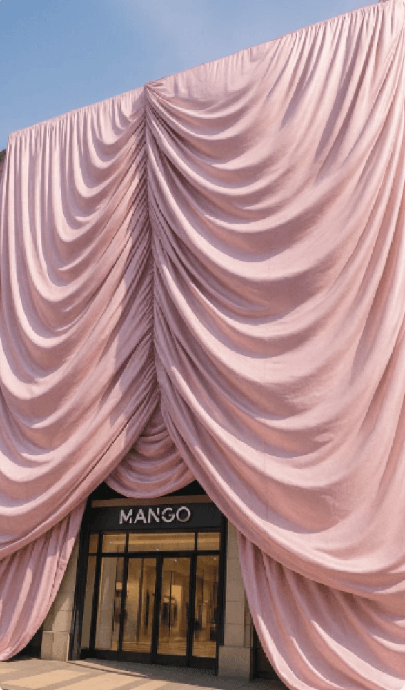 A realistic render of the "Mango" storefront partially covered by elegant, flowing pink curtains